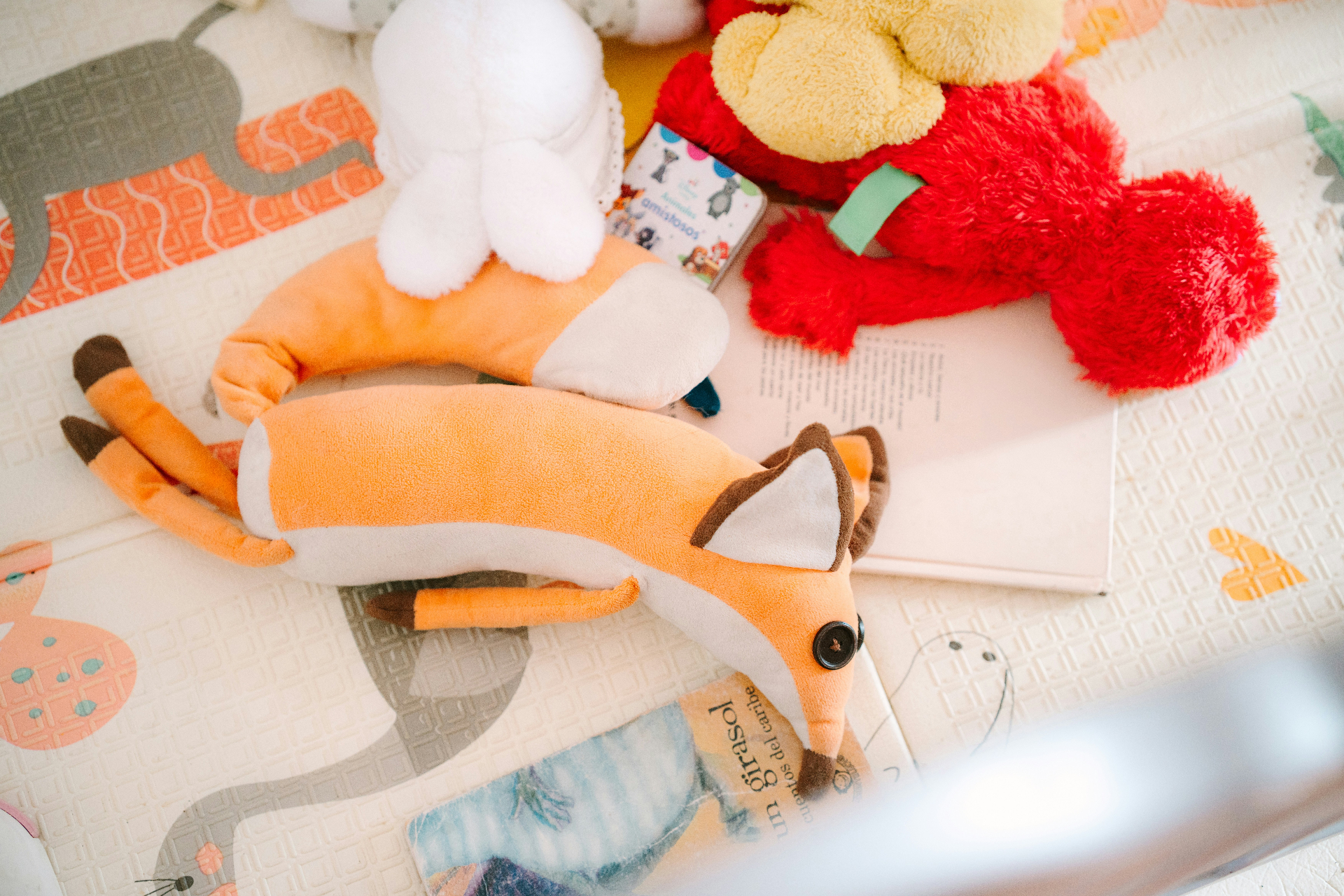 Peluches et livres pour enfants sur un tapis d'éveil